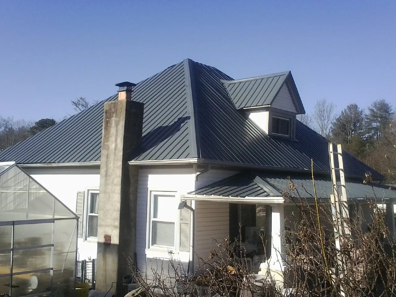 Dark blue standing seam metal roof on a white farmhouse with dormer — Slate & Tile Roof Repair by Roofing Brothers in Sumava Resorts