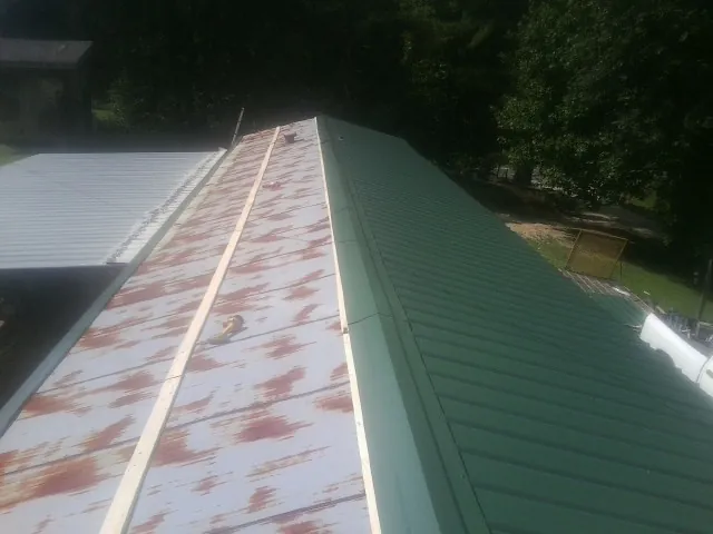 Old rusted panels beside newly installed green metal roofing — Wind Damage Roof Repair by Roofing Brothers in Sumava Resorts