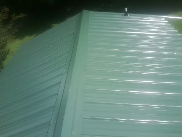 New green metal panels meeting at the ridge of a roof — Flat Roof Repair work by our crew in Sumava Resorts