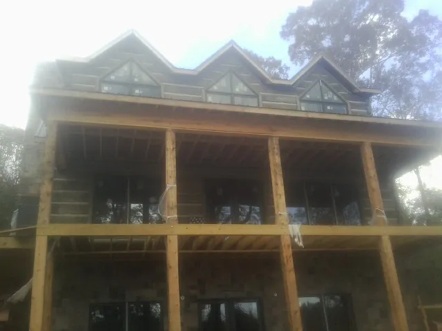 Dormers and porch framing on a large log home under construction — Roof Coating work by our crew in Sumava Resorts