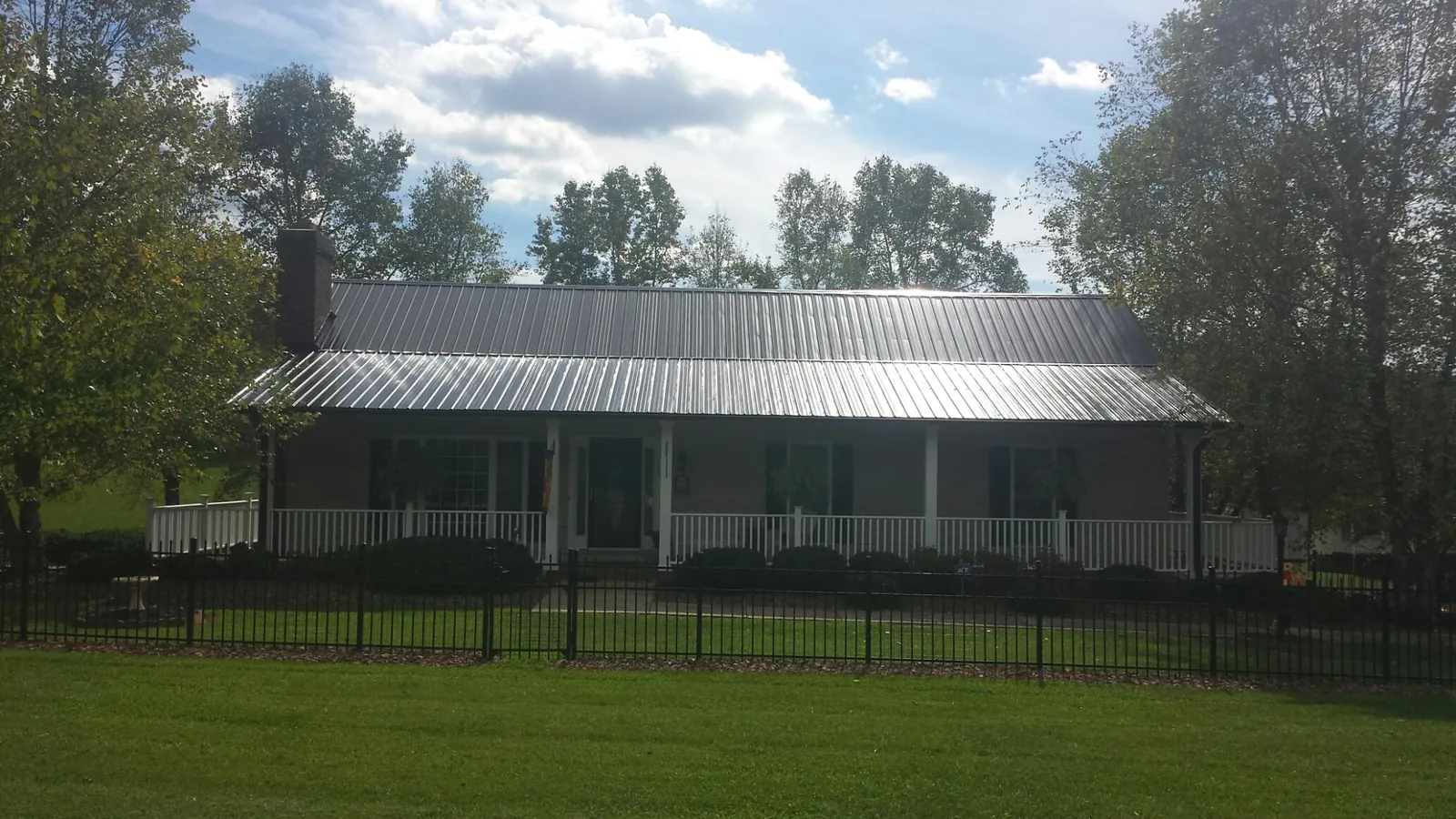 Gray metal roof on a brick ranch with a full width front porch — Gutter Guard Installation work by our crew in Sumava Resorts