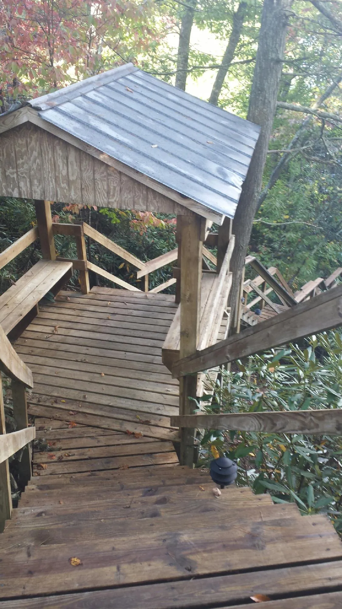Metal roofed shelter over wooden steps on a wooded walkway — Skylight Repair & Installation work by our crew in Sumava Resorts