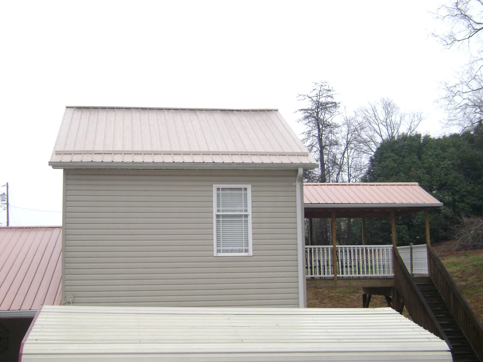 Tan metal roofs on a two story addition and attached porch, from a Roof Replacement job in Sumava Resorts