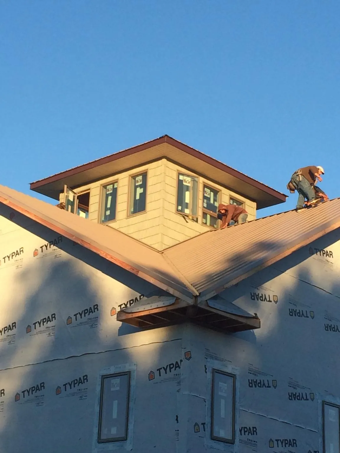 Roofers working around a rooftop cupola on a new metal roof at sunset — Roof Waterproofing in Sumava Resorts by Roofing Brothers